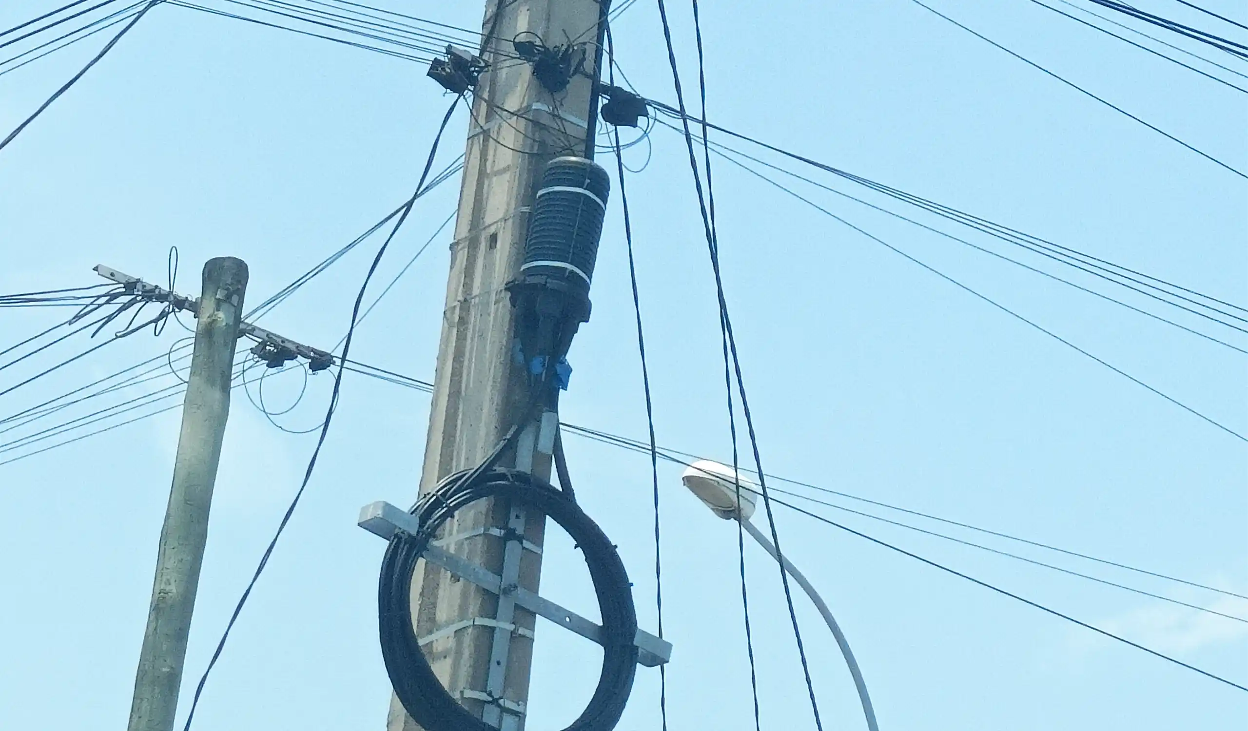 dome type fiber optic splice closure installed on a concrete pole with cable storage bracket.
